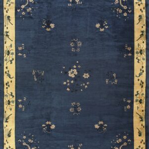 Navy blue rug with scattered light floral patterns and a wide tan border with stylized bird motifs.