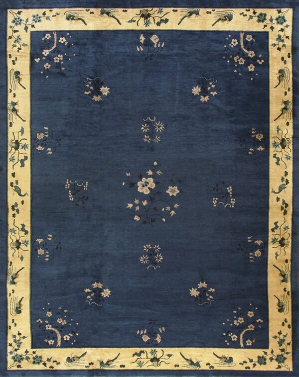 Navy blue rug with scattered light floral patterns and a wide tan border with stylized bird motifs.