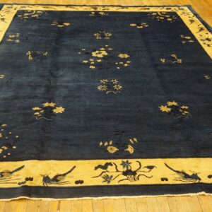 A large navy blue rug with scattered gold floral motifs and a wide golden border on wood flooring.