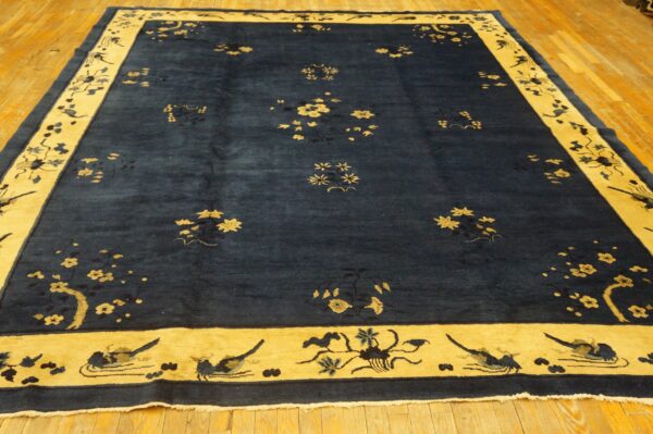 A large navy blue rug with scattered gold floral motifs and a wide golden border on wood flooring.