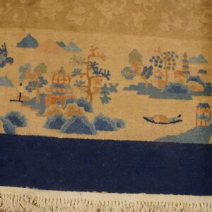 Tan rug border displays a landscape pattern in blue and peach, above a thick navy edge and beige fringe.