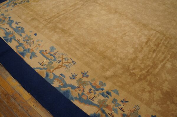 Gold-toned rug with a subtle field pattern and wide border featuring blue and peach landscapes.