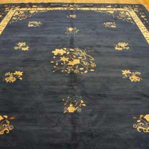 Large indigo rug featuring gold floral medallions and a broad border on light brown hardwood flooring.