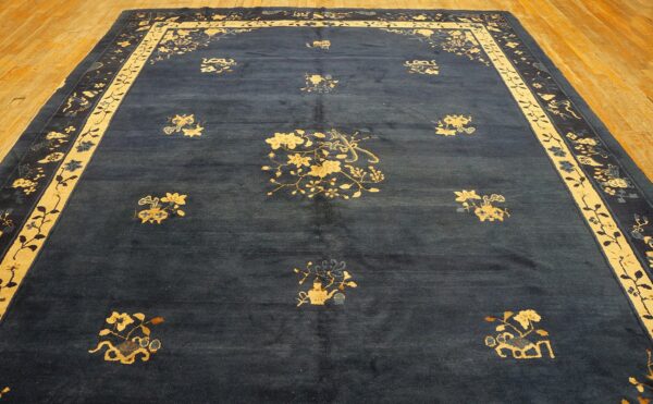 Large indigo rug featuring gold floral medallions and a broad border on light brown hardwood flooring.