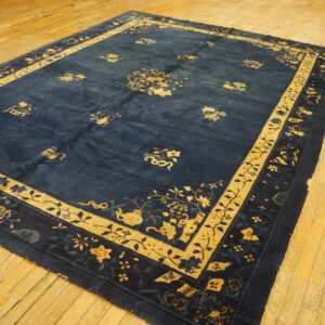 Blue and yellow patterned area rug with a wide border displayed on light-colored wooden floorboards.