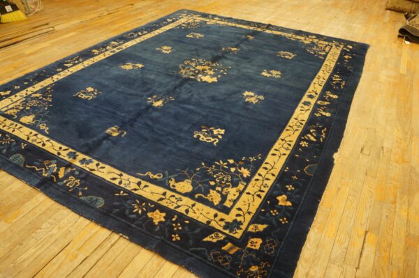 Blue and yellow patterned area rug with a wide border displayed on light-colored wooden floorboards.