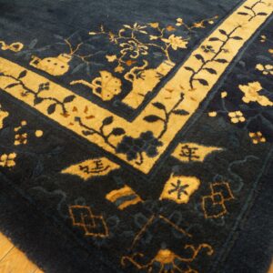 A thick, plush blue rug with intricate gold borders and floral patterns rests on golden hardwood flooring.