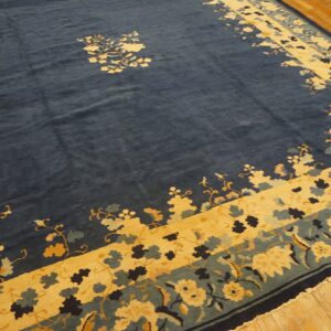 Blue rug featuring central florals and wide yellow and teal floral borders on wooden planks.