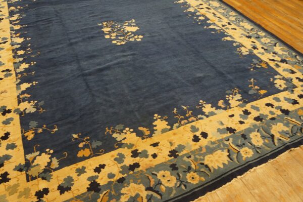 Blue rug featuring central florals and wide yellow and teal floral borders on wooden planks.