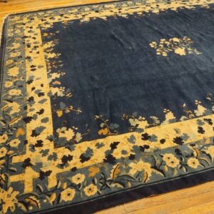 A deep indigo rug featuring a large gold and teal floral border on natural wood flooring.