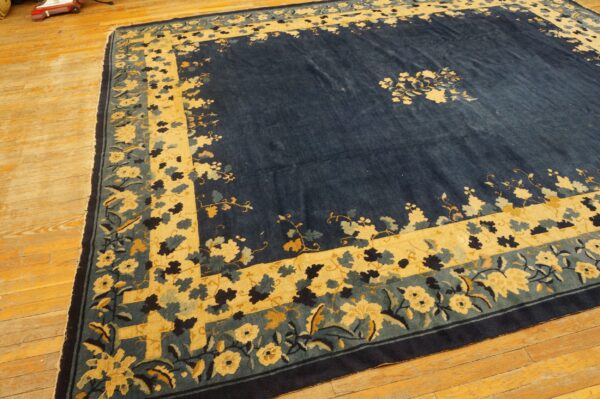 A deep indigo rug featuring a large gold and teal floral border on natural wood flooring.