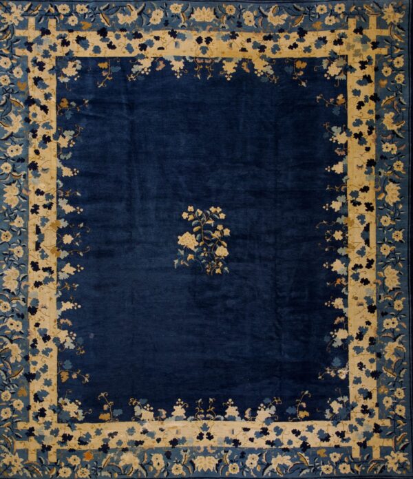 Navy blue rug with a central cream floral spray and broad borders of cream and multi-toned blue floral motifs.