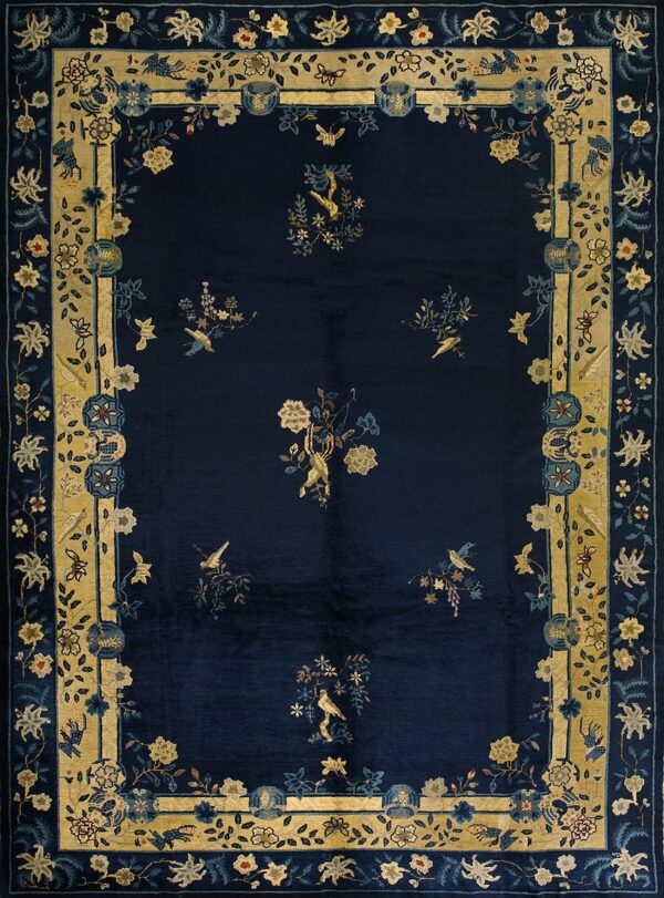 Dark blue rug featuring scattered floral sprigs and birds, framed by a broad gold and light blue ornamental border.
