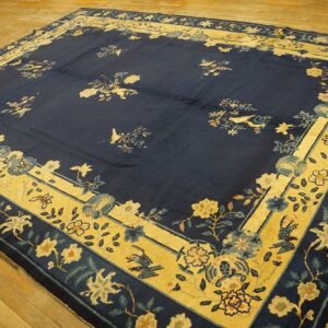 Large navy rug featuring floral and bird patterns with wide golden-yellow borders on wood flooring.