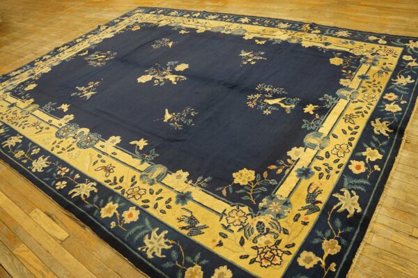 Large navy rug featuring floral and bird patterns with wide golden-yellow borders on wood flooring.