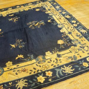 Dark blue rug featuring light yellow borders, florals, and birds, placed over bright wood flooring.