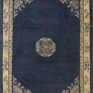 Navy blue rug featuring a central floral medallion and detailed light tan borders with blue designs.