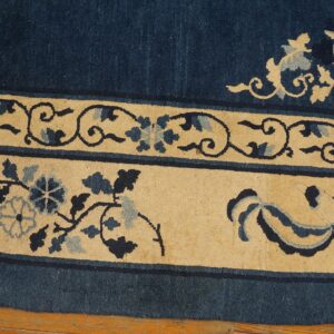 This rug detail highlights the deep blue field bordered by cream panels with intricate floral patterns.