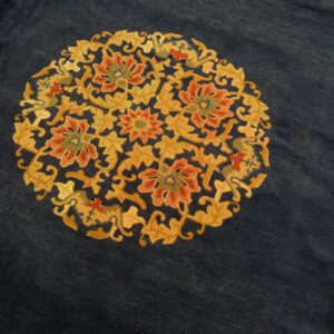 Dark indigo rug surface with a central circular medallion of dense gold and coral floral patterns.