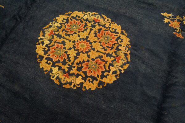 Dark indigo rug surface with a central circular medallion of dense gold and coral floral patterns.