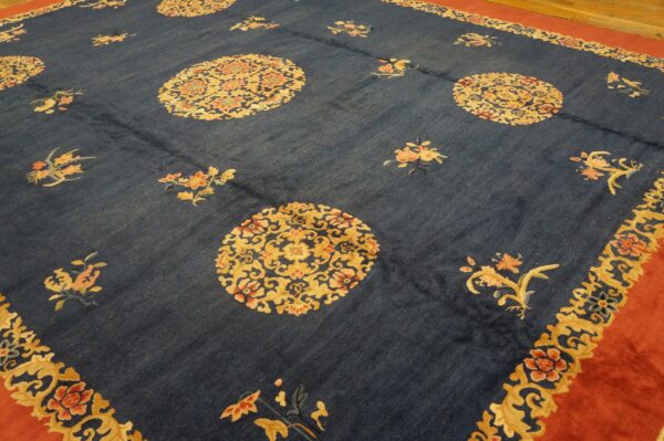 Navy blue rug featuring repeating floral medallions in gold and coral with a wide rust red border.