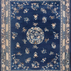 Dark blue rug featuring a central medallion and scattered floral motifs in cream, tan, and light blue.