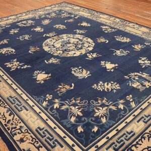 Large navy rug featuring cream and light blue floral patterns, set on a light brown wood floor.