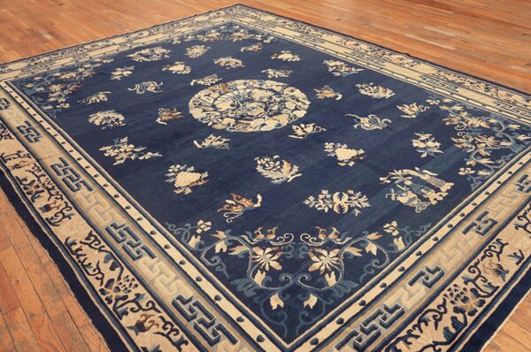 Large navy rug featuring cream and light blue floral patterns, set on a light brown wood floor.