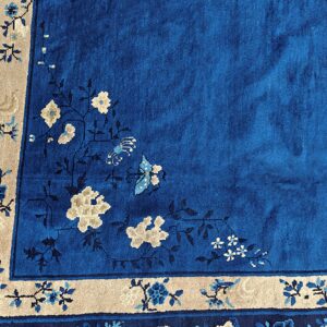 Close-up of a blue rug with a plush pile and intricate floral patterns in beige and light blue.