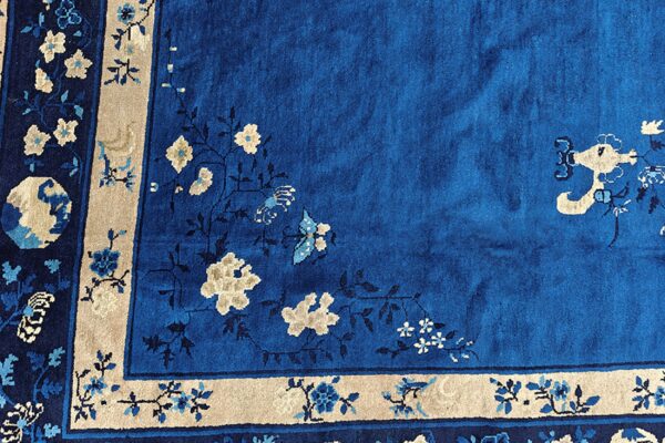 Close-up of a blue rug with a plush pile and intricate floral patterns in beige and light blue.