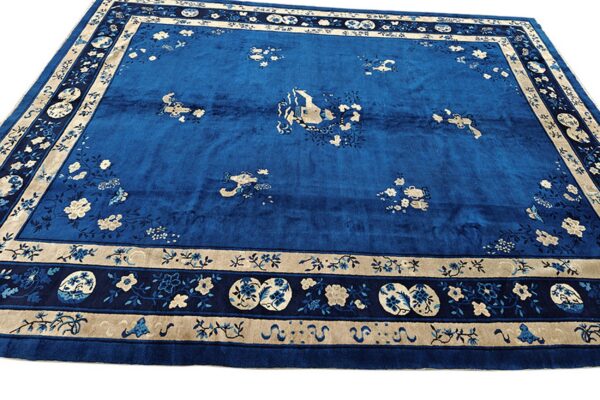 High-pile royal blue rug with scattered beige floral motifs and a complex multi-banded border.