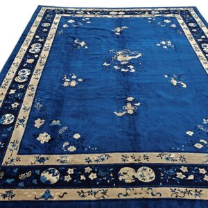 Sapphire blue rug featuring scattered beige floral and landscape motifs, framed by a wide patterned border.
