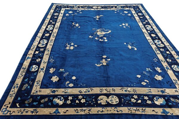 Sapphire blue rug featuring scattered beige floral and landscape motifs, framed by a wide patterned border.