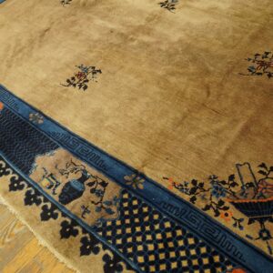 A golden-tan rug features scattered floral motifs and a complex blue, indigo, and orange patterned border on wood planks.