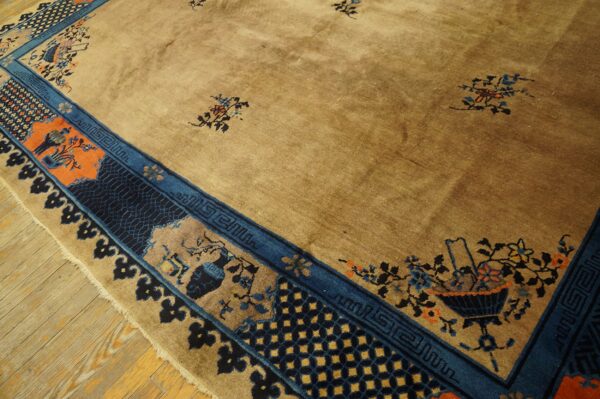 A golden-tan rug features scattered floral motifs and a complex blue, indigo, and orange patterned border on wood planks.