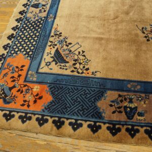A corner of a tan rug displaying a detailed blue, orange, and teal geometric border on distressed wood flooring.