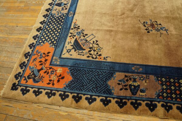 A corner of a tan rug displaying a detailed blue, orange, and teal geometric border on distressed wood flooring.