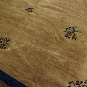 Distressed khaki rug with low pile features small colorful floral sprays and a wide blue border.
