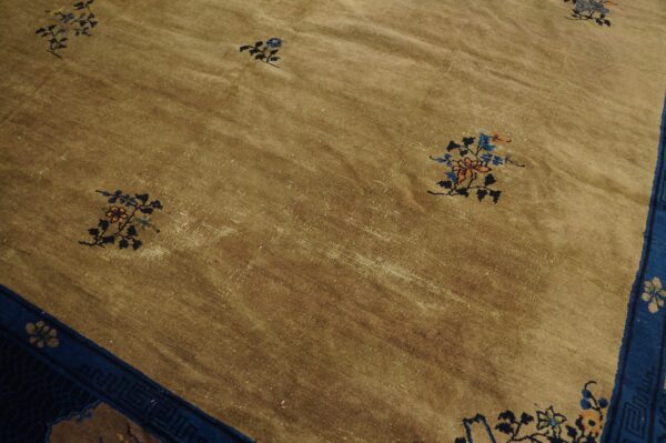 Distressed khaki rug with low pile features small colorful floral sprays and a wide blue border.