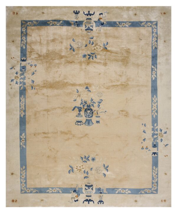 High-sheen beige rug featuring blue floral and vase designs within a thick blue rectilinear border.