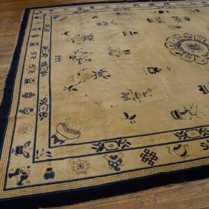Tan low-pile rug with blue scattered symbols and a medallion on rustic wood plank flooring.