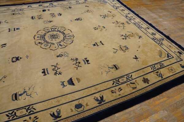 Tan rug with navy borders and blue scattered vase and floral motifs on rustic wood planks.