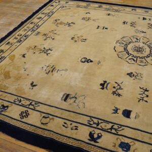 Low-pile beige rug with dark blue scattered symbols and borders lies on rustic wood flooring.