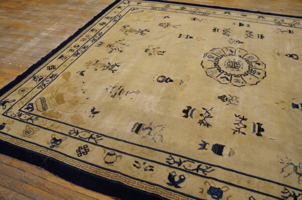 Low-pile beige rug with dark blue scattered symbols and borders lies on rustic wood flooring.