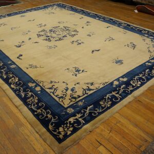 Yellow-cream rug featuring blue floral sprigs, a central medallion, and an ornate triple border on wood planks.