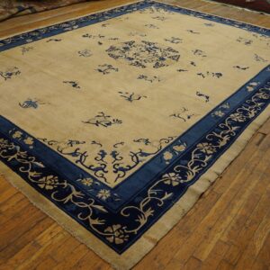 A cream rug with scattered blue florals and a wide indigo border rests on distressed wood planks.