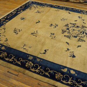 A golden yellow rug with a dark blue floral border and scattered blue motifs lies on wooden floorboards.