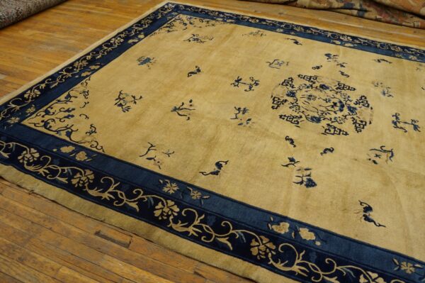 A golden yellow rug with a dark blue floral border and scattered blue motifs lies on wooden floorboards.