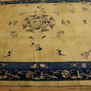 Golden rug with dark blue stylized scattered motifs, central medallion, and an intricate floral border on wood.
