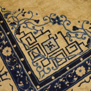 Golden tan rug border with dark blue floral design and blue geometric meander patterns.